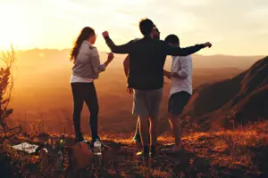 Friends enjoying a sunset on a mountain, capturing a moment of joy and connection in nature.