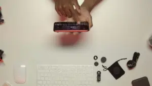 Person adjusting a camera on a desk with various photography accessories and a keyboard in the background.