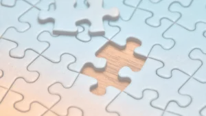 Close-up of blue jigsaw puzzle pieces with one piece missing, revealing a wooden surface underneath.