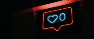 Neon sign displaying a heart and zero in a speech bubble, symbolizing love and social media engagement at night.