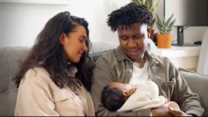 Young parents lovingly gazing at their newborn baby, creating a warm family moment at home.