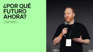 Man speaking at a conference with a microphone, presenting on a topic about the future on a green background.