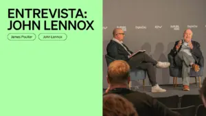 John Lennox speaking at a panel discussion, hosted by James Poulter, with a modern staged backdrop.