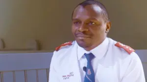 A uniformed volunteer in a well-lit room, wearing a white shirt and blue tie, engaged in an important conversation.