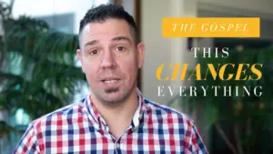 Man in checkered shirt speaking, with text overlay "The Gospel - This Changes Everything" and green plants in background.