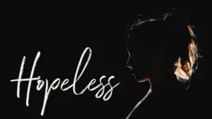 Silhouette of a woman with the word "Hopeless" displayed artistically, conveying emotion and depth in a dark setting.