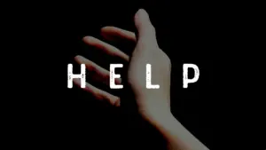 A close-up of a hand reaching out against a dark background with the word "HELP" prominently displayed.