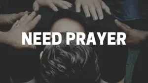 Hands placed on a person's head in a gesture of prayer and support, highlighting a moment of spiritual need.