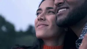 Couple enjoying a moment together outdoors, smiling and looking toward the sky with a soft, romantic atmosphere.