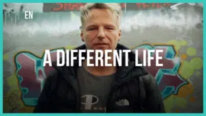 Man standing in front of colorful graffiti, promoting the theme of transformation and new beginnings in life.