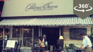 Charming café exterior with outdoor seating, featuring a striped awning and inviting storefront ambiance.