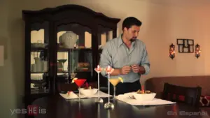 Man preparing cocktails at a dining table with colorful drinks and decorative dishes in an elegant home setting.