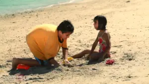 Children playing in the sand on a beach, building a sandcastle under the sun.