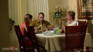 Family enjoying a meal together at a dining table, surrounded by flowers and a warm, inviting atmosphere.