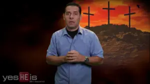 Man in a blue shirt standing in front of three crosses against a dramatic sunset background, conveying a religious theme.