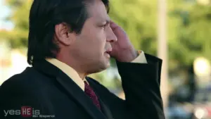 Businessman in a suit with hand on forehead, looking thoughtfully outdoors in soft natural light.