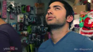 Man with dark hair looking up in a colorful store filled with various products, showing a thoughtful expression.