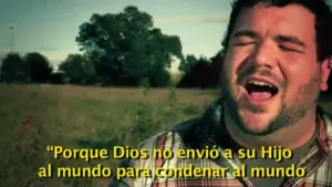 Man singing passionately outdoors, with fields and trees in the background, expressing a heartfelt message.