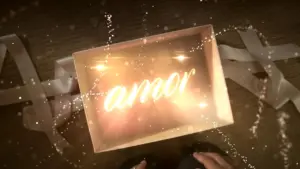 A glowing box reveals the word "amor" surrounded by sparkles and ribbons on a wooden surface.