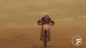 Motorcycle rider performing a jump over sandy terrain under a dramatic sky, showcasing thrill and adventure.