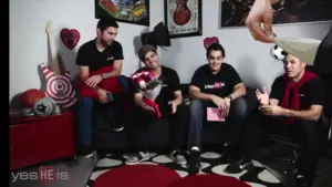 Four young men in casual black shirts seated on a couch, surrounded by colorful decor and playful accessories.