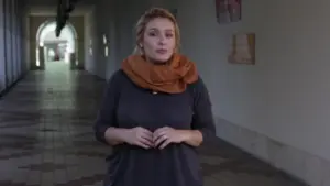 Woman with a stylish scarf stands confidently in a hallway, showcasing a modern and inviting atmosphere.