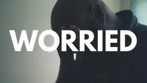 A person with a worried expression, hand on forehead, against a soft-focus background emphasizing the word "WORRIED."