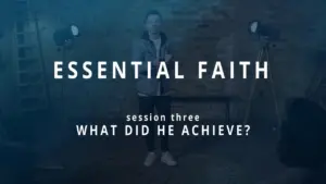 A speaker stands in a studio setting, discussing achievements in an "Essential Faith" session.