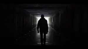 Silhouette of a person walking towards a bright light in a dark corridor, creating a mysterious atmosphere.