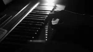 A close-up of a hand playing black and white piano keys, creating a dramatic and artistic music scene.