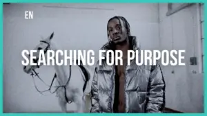 A man in a silver jacket stands beside a white horse, with the text "Searching for Purpose" displayed prominently.