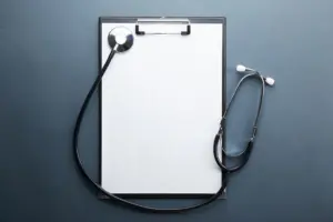 Stethoscope and blank clipboard on a blue background, representing healthcare and medical documentation.