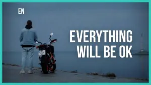 Person standing next to a motorcycle by the water with text overlay saying "Everything will be OK."