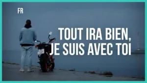 Person standing next to a motorcycle by the water with the text "Tout ira bien, je suis avec toi" in the background.