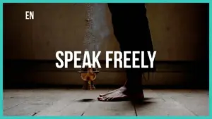 Person standing barefoot on a wooden floor with the text "SPEAK FREELY" prominently displayed above.