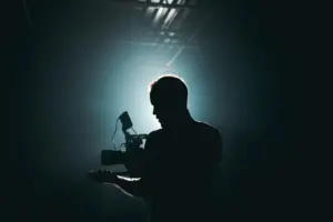 Silhouette of a photographer holding a camera against a dramatic blue light background.