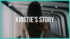 Woman walking through a modern corridor, text overlay reads "Kirstie's Story" highlighting a personal journey.