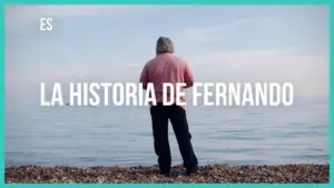 A person standing by the shore, gazing at the calm sea, with the title "La Historia de Fernando" overlayed.