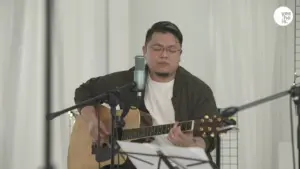 Musician performing on acoustic guitar in a studio setting, capturing an intimate musical atmosphere.