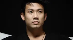 Young man with a serious expression, featuring dark hair and a minimalist background, conveying a sense of introspection.