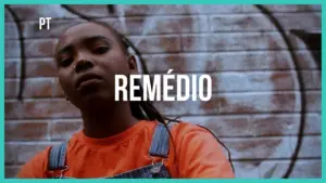 Young person in an orange shirt poses confidently against a graffiti backdrop with the word "REMÉDIO" displayed prominently.