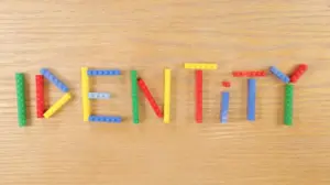 Colorful Lego bricks spelling the word "IDENTITY" on a wooden surface, emphasizing creativity and individuality.