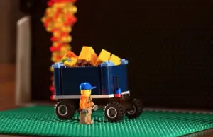 Colorful Lego truck with a figure collecting blocks, set against a vibrant background of falling bricks.