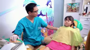 Pediatric dentist interacting with young girl in a colorful dental clinic, promoting a friendly and caring atmosphere.