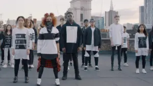 Diverse dance group performing on a rooftop with a city skyline backdrop, showcasing unity and urban style.