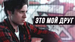 Young man in a flannel shirt looking pensive against a colorful graffiti backdrop with bold text in Russian.