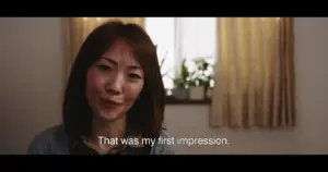 Woman sharing her first impression in a well-lit room with plants and curtains, conveying a personal storytelling moment.