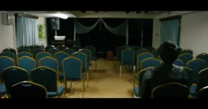 Empty auditorium with blue chairs facing a stage, spotlighted for a performance, creating an inviting atmosphere.