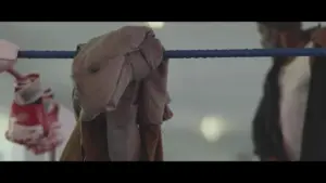 Worn boxing gloves and a towel hanging on a blue rope in a gym, capturing the essence of training and dedication.