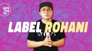 Young man speaking passionately against a bright pink background, promoting the "Label Rohani" initiative.